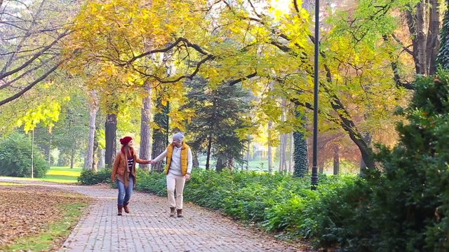 Romantic young couple walking in the park, walking, kissing and holding hands. Slow motion.