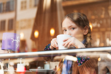Little girl drinking hot chocolate in a cafe