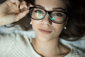 Fototapeta premium Cute woman in glasses lies on bed
