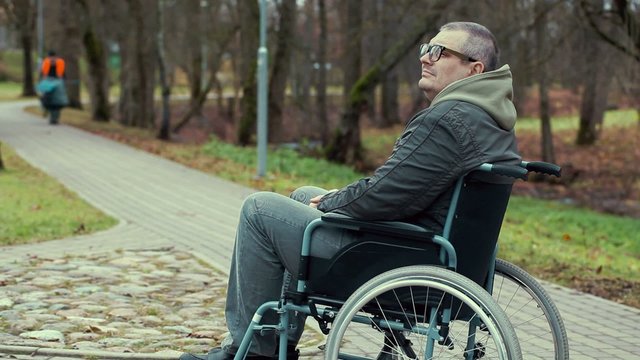 Disabled man in wheelchair waiting on path in the park