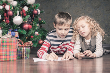 Naklejka premium Boy and girl lying on the floor under Christmas tree
