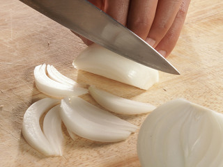cut onion on chopping board by knife close up finger 