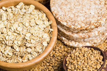 Variety of grains: rolled oats, golden linseeds (flax seeds), whole wheat grains and buckwheat cakes. Soft focus