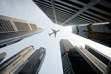 Fototapeta na wymiar Tall city buildings and a plane flying overhead