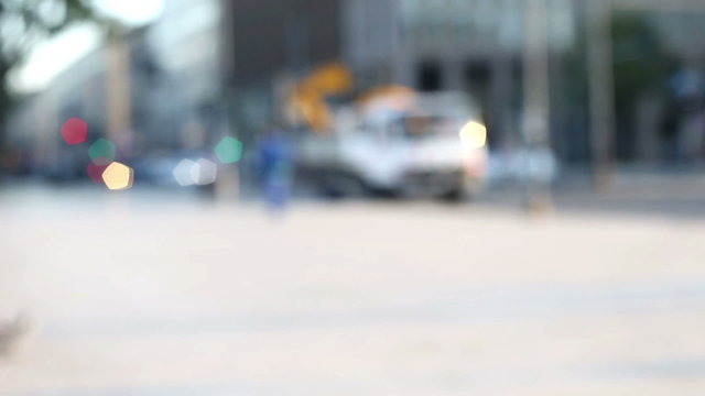 few people walking alone in a street near traffic lights  in a blurred and out of focus background, urban context