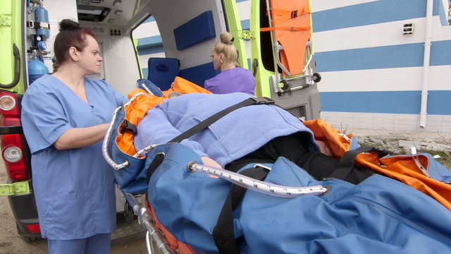 Emergency medical ambulance service paramedics crew fixing senior patient on stretcher collapsible vacuum mattress with safety belts