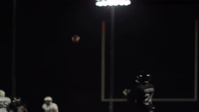 A football player almost misses a pass and then makes a touchdown and lays on the ground