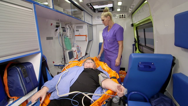 EMT professional provide emergency medical care for senior cardiac patient in ambulance 