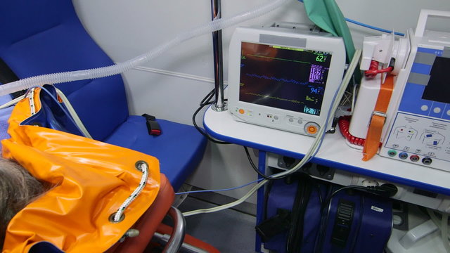 Paramedic monitoring obese senior patient condition in ambulance during transportation