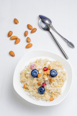 Oatmeal porridge with berries and nuts in bowl, top view