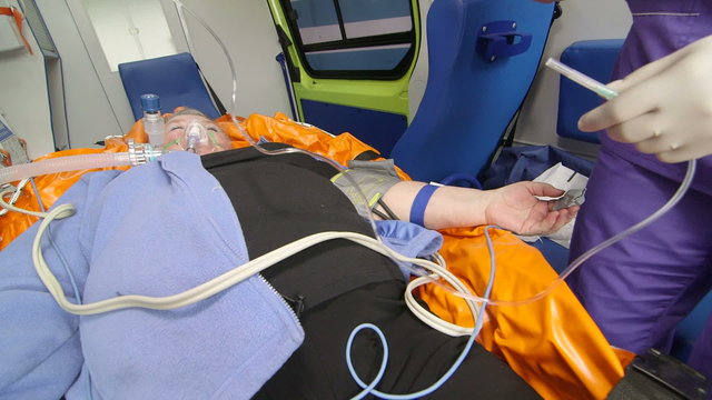 EMT provide emergency medical care to patient in ambulance preparing intravenous infusion