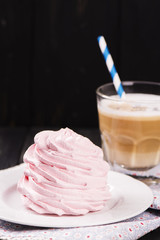 Coffee latte with crunchy pink meringue over black wooden background. Tasty breakfast concept. Selective focus, toned image