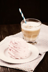 Coffee latte with crunchy pink meringue over black wooden background. Tasty breakfast concept. Selective focus, toned image