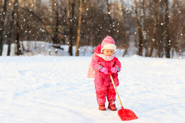 Fototapeta na wymiar cute little toddler girl dig in winter snow