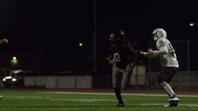 A football player runs hard to catch the football during a game