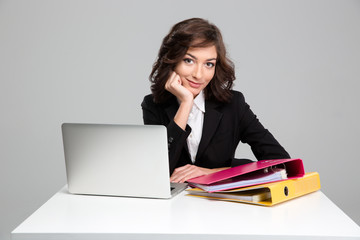 Beautiful smiling business woman using laptop and binders