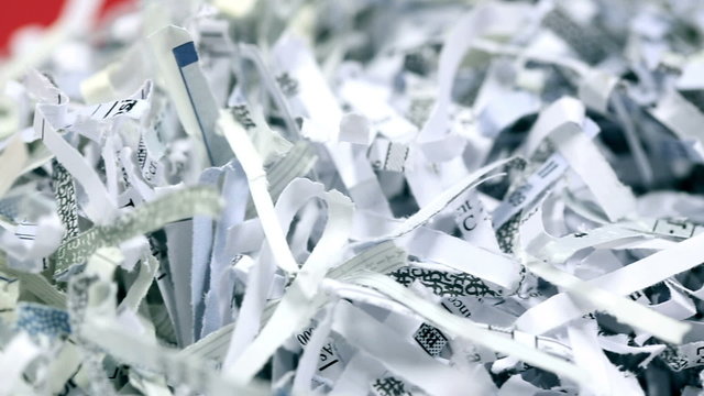 Shredded Paper Macro. moves right on a stack of shredded paper on a red background. second shot camera moves left on a stack of shredded paper.
