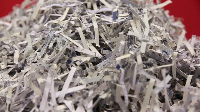 Shredded Paper Right Pan Slow. camera rotates slowly around a stack of shredded paper on a red background. macro shallow depth of field
