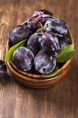 Autum or harvest concept: wooden bowl full of ripe plums. Selective focus