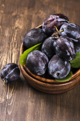 Autum or harvest concept: wooden bowl full of ripe plums. Selective focus
