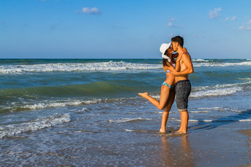 Fototapeta premium Attractive young couple in bikini and shorts at the beach.