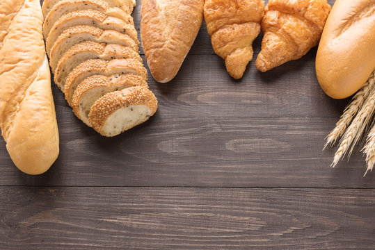 Fresh baked bread and wheat on wooden background