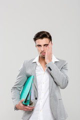 Exhausted young man holding binders