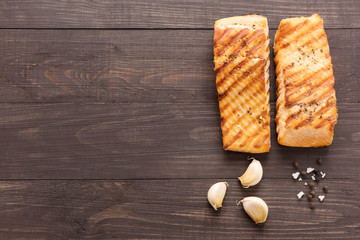 Grilled salmon with garlic, pepper, salt on wooden background