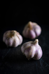 Garlic bulbs on black wooden board, soft focus, close up