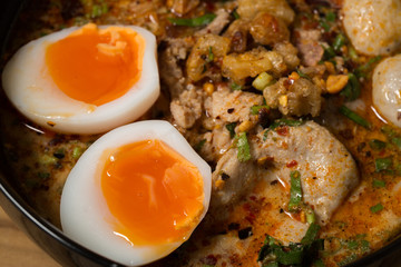 bowl of noodles with vegetables and soft boiled egg on wooden ta