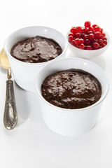 chocolate pudding in white cups with red current . healthy desse