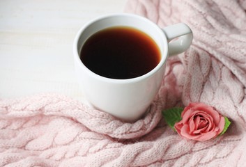 White cup of coffee framed by knitted woollen scarf, cozy winter morning at home