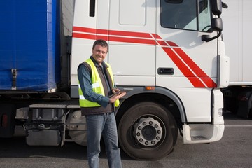 Male contractor on his tablet while standing by  truck