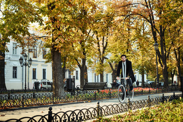 young caucasian businessman riding bicycle