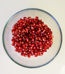 Pomegranate seeds, juicy fruit in a glass container.