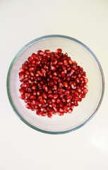Pomegranate seeds, juicy fruit in a glass container.