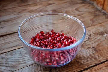 Pomegranate seeds, juicy fruit in a glass container.