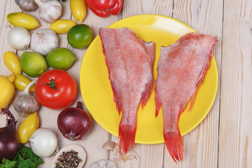 two raw fishes of bass with lime,.by tomatoes, pepper, onion, lemon, basil,.by a garlic, parsley and spices