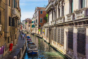 Narrow canal among old colorful brick houses in Venice