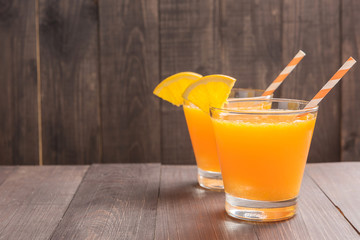 Fresh orange juice and oranges on wooden table