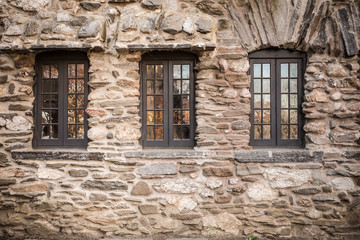 Rough stone castle wall and three windows