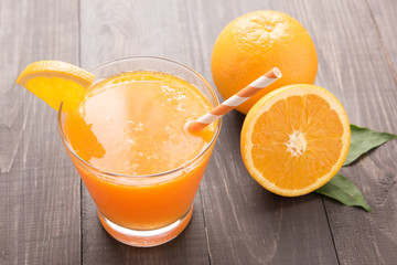 Fresh orange juice and oranges on wooden table