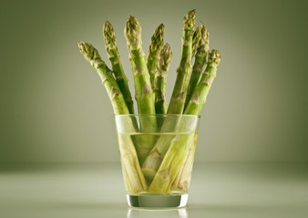 Fresh raw asparagus spears in glass of water