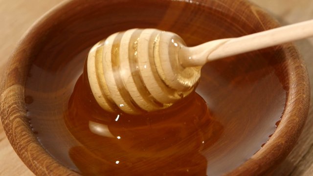 Using spoon for honey in wooden bowl