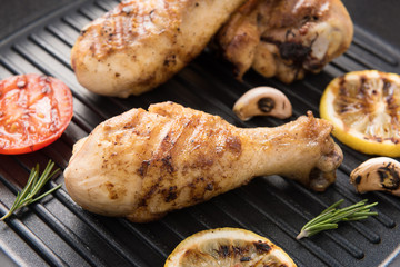 Grilled chicken drumstick and vegetables in a pan.