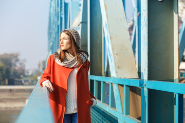 Portrait of a beautiful young brunette woman on the bridge, she is looking at distance.