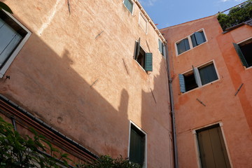 Fototapeta na wymiar Old orange wall with green shutters on windows
