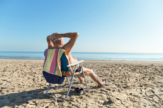 Old man sunbathing at the beach