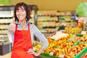 Ältere Verkäuferin hält Daumen hoch im Supermarkt