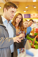 Mann an Kasse vom Supermarkt hat Geld vergessen